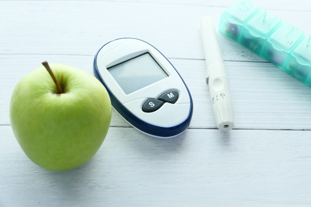 Close up of diabetic measurement tools, apple and pill box on table